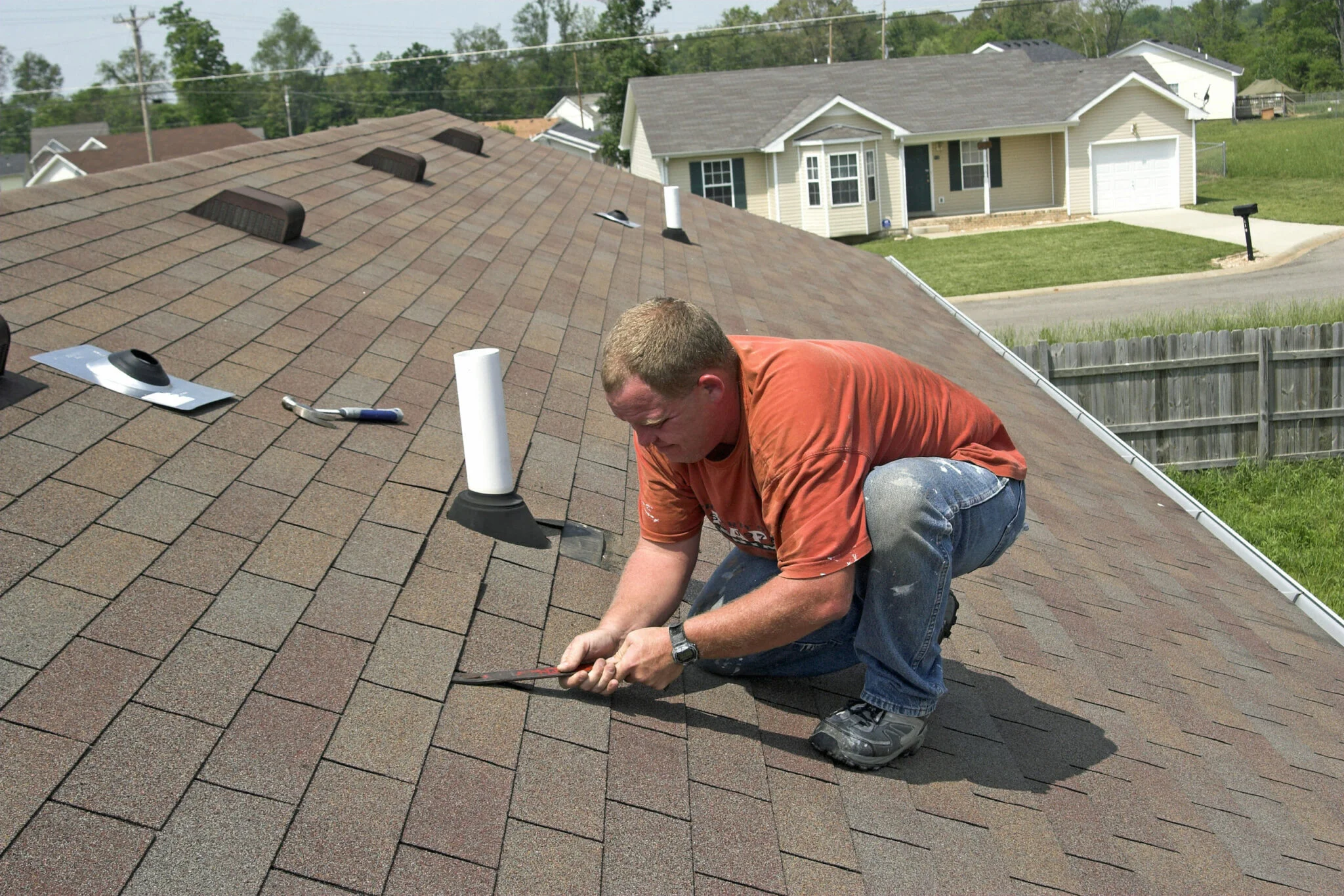 Man repairing shingles on roof.