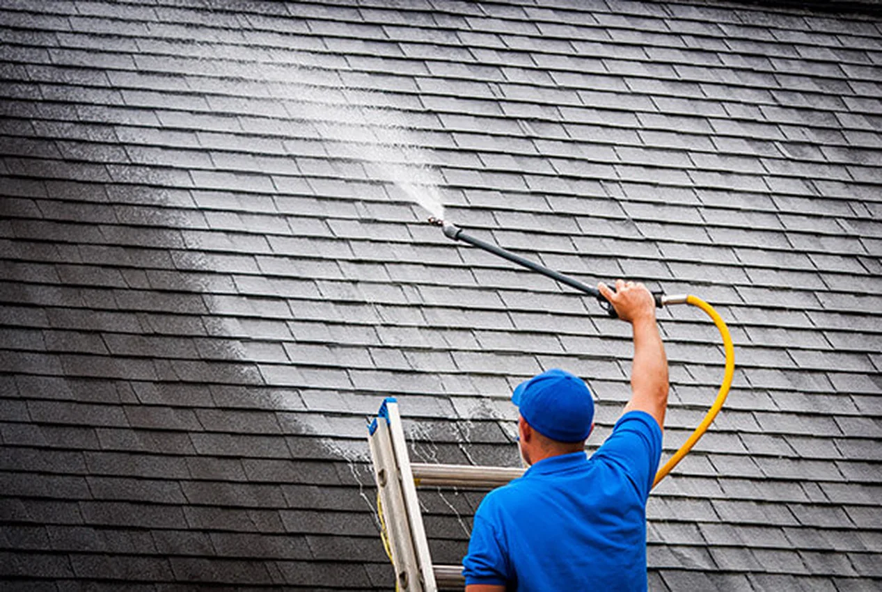 Man cleaning roof with pressure washer